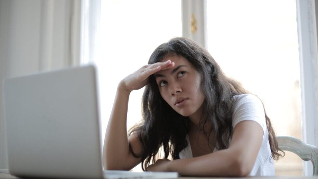 a woman stressfully looking upwards with her hand rested on her head