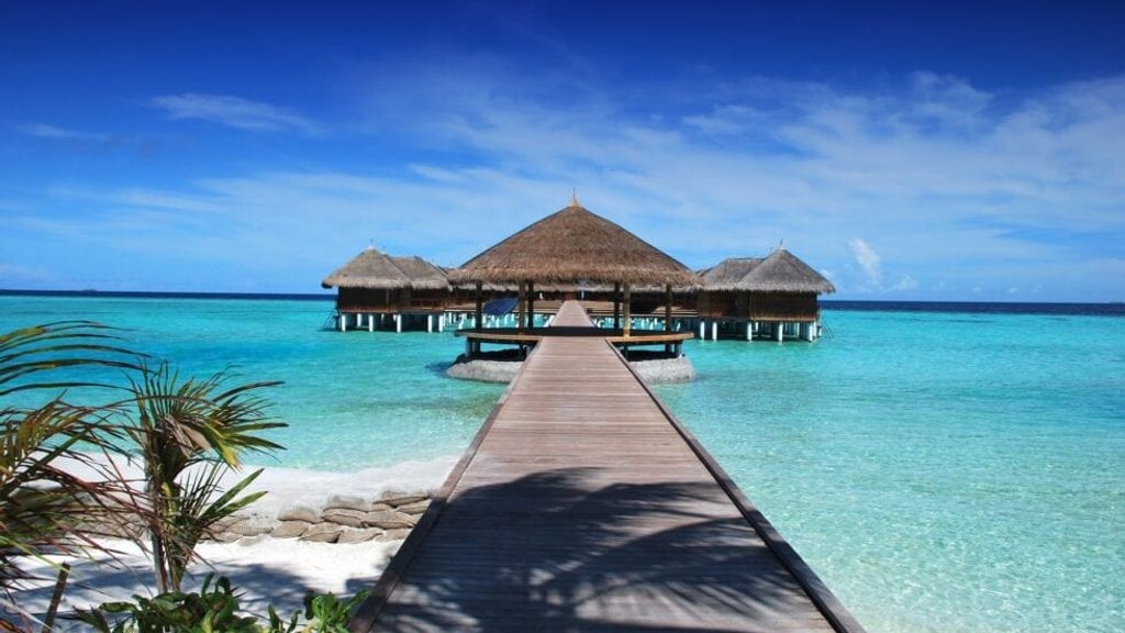 A photo of a hut out on a bright blue sea in a holiday destination