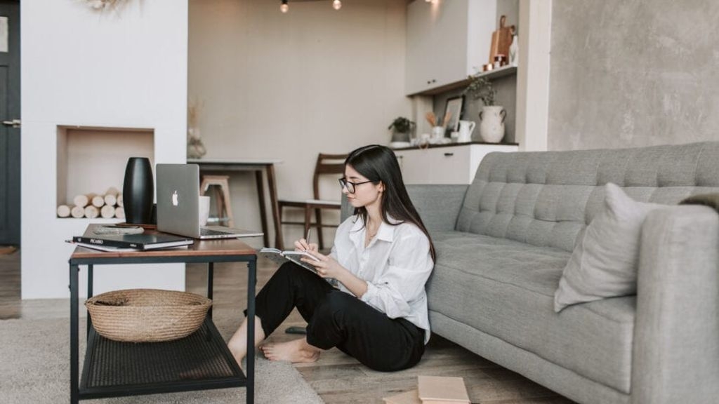 A woman sat comfortably on floor working from home